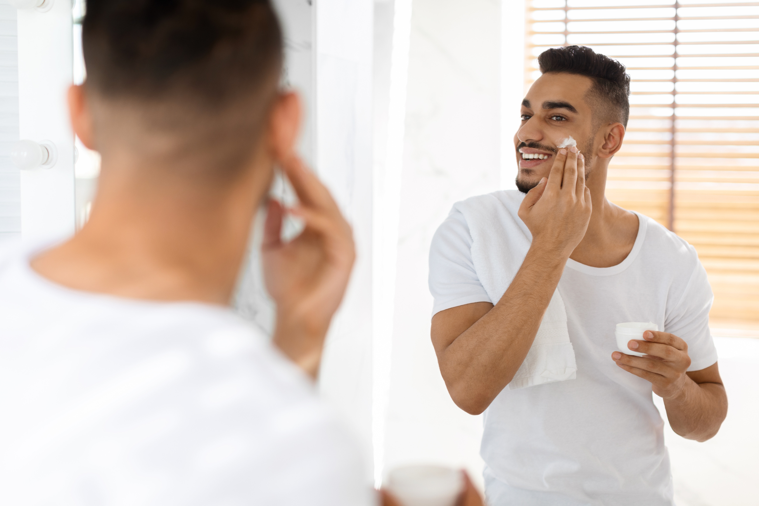 Male Beauty Care. Handsome Young Arab Man Applying Moisturising Face Cream